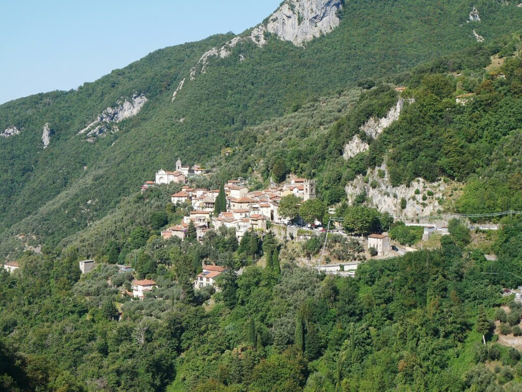 Il borgo di Casoli con le case, i campanili e i boschi ai piedi delle pareti rocciose delle Alpi Apuane