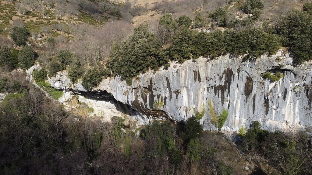 La parete calcarea e l’apertura della Grotta all’Onda tra la vegetazione alle pendici del Monte Matanna